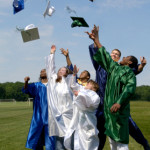 Group of graduates toss their hats into the sky with jubilation. There is a small hint of blur in the motion of the toss.