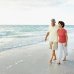 Loving mature man and woman walking at water's edge on a beach