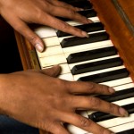 black woman with long exquisite fingers playing an old piano