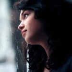 Beautiful girl looks out of the window. On its lips an easy smile, and behind a window a rain.