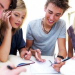 Group of happy young boys and girls sitting together with notes