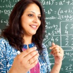 Young Cheerful Indian Mathematics Teacher in a Classroom interacting with the class